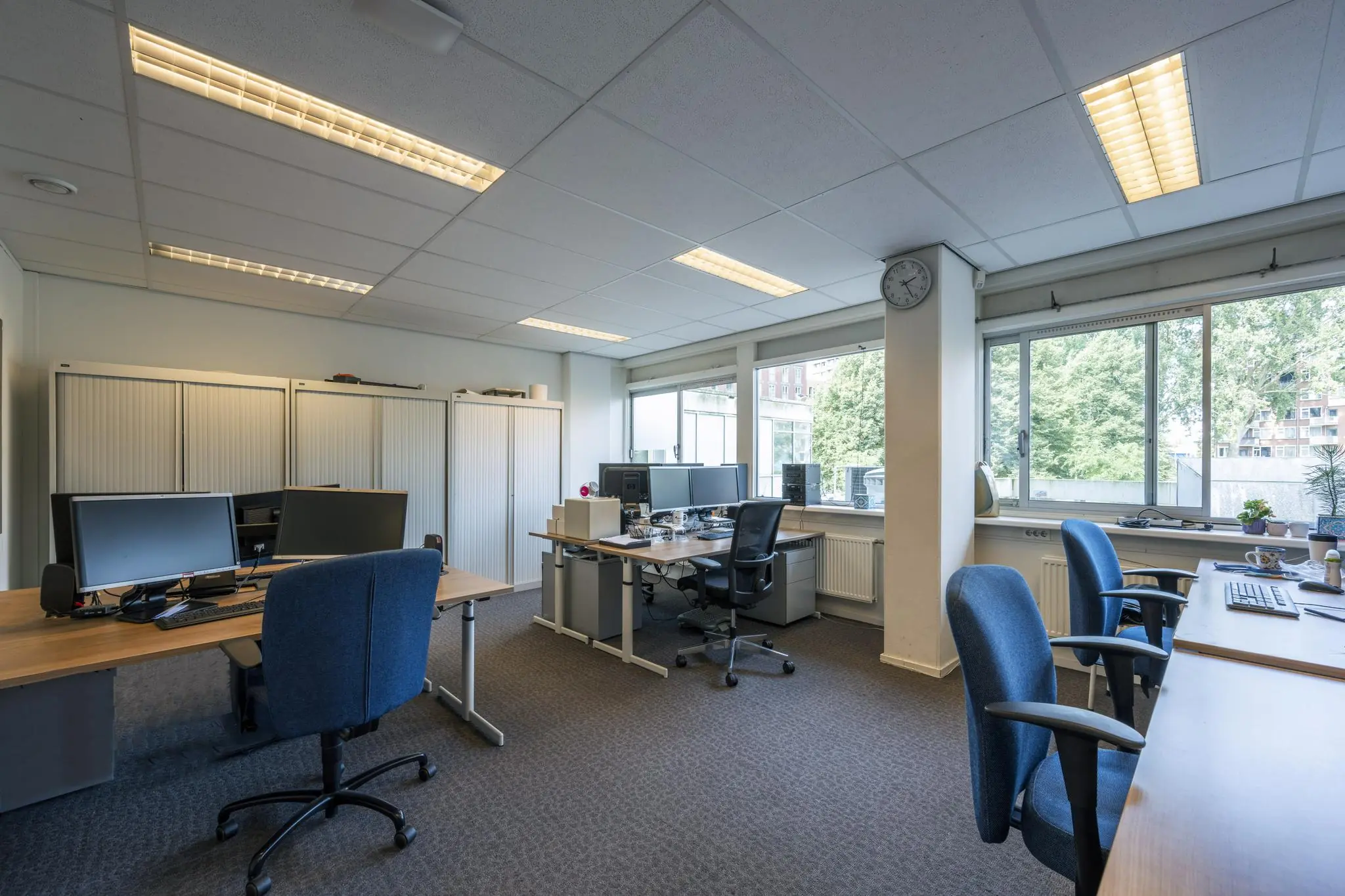 Modern ingericht kantoorpand aan de Jan Tooropstraat met meerdere werkplekken en grote ramen met uitzicht op groen.